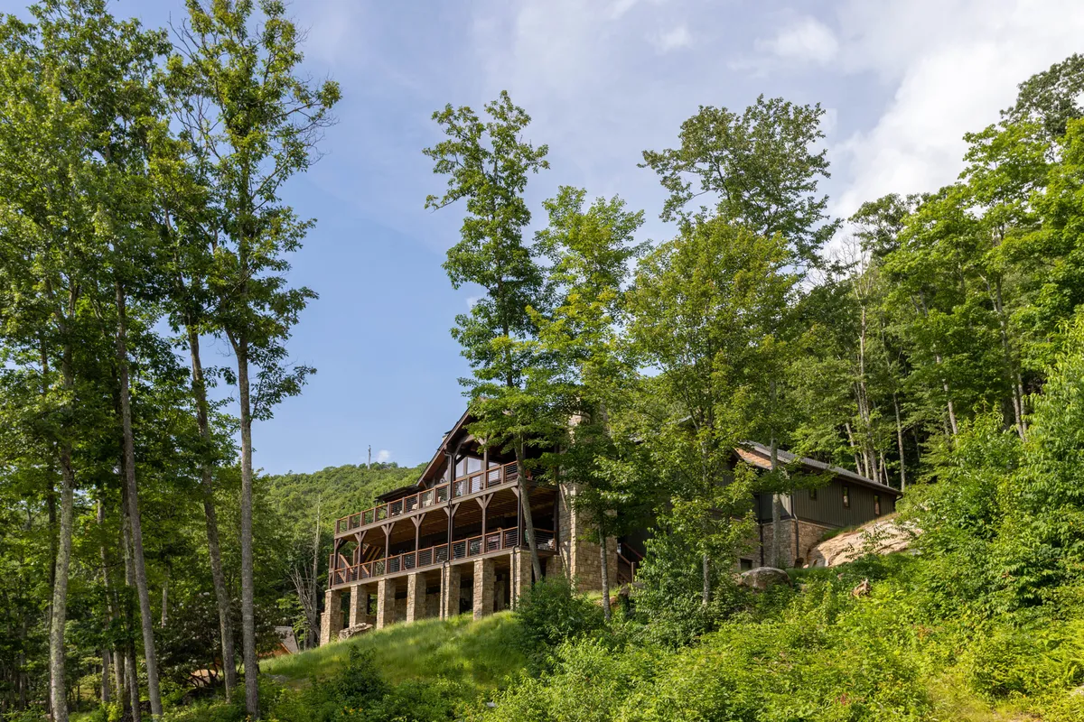 A tranquil exterior view of a spacious wooden deck, expansive windows, and surrounding trees. The deck offers space for relaxing, wildlife watching, or hosting gatherings, blending seamlessly with the natural surroundings.