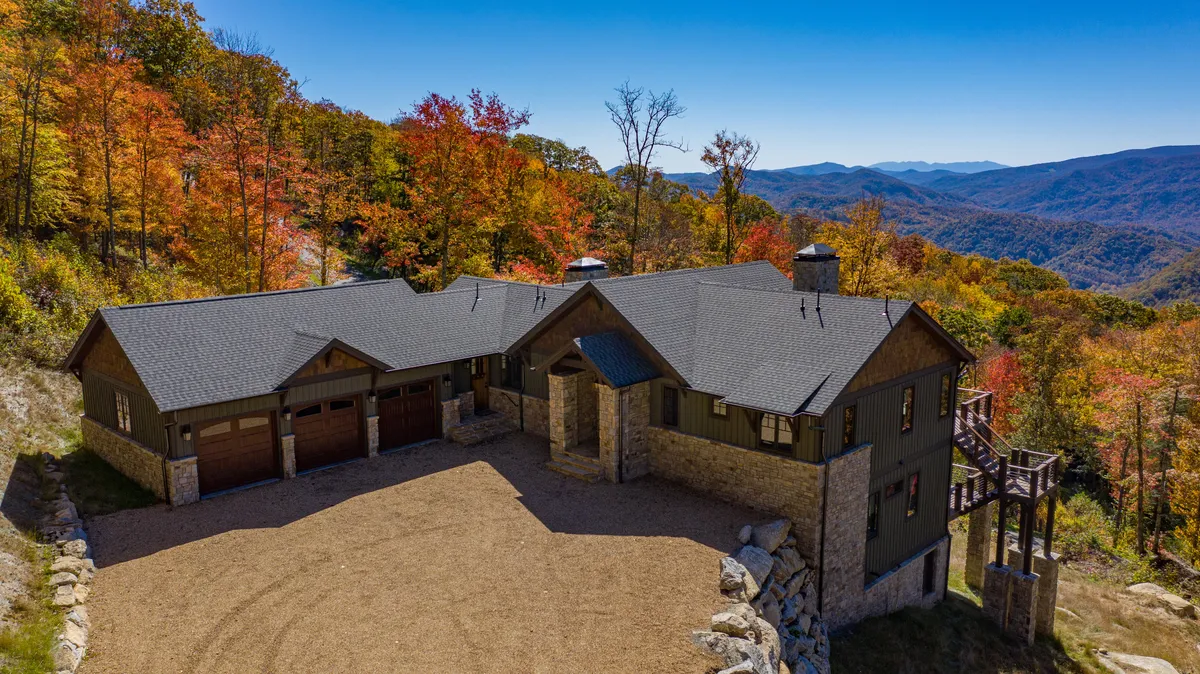 The hero image showcases a stunning, custom-built mountain home nestled among vibrant autumn trees, with panoramic views of rolling mountains in the background. The spacious deck overlooks the Elk River Valley, inviting guests to enjoy sunsets, stargazing, and peaceful moments surrounded by nature. The house itself exudes luxury and warmth, perfectly positioned for both relaxation and outdoor adventure.